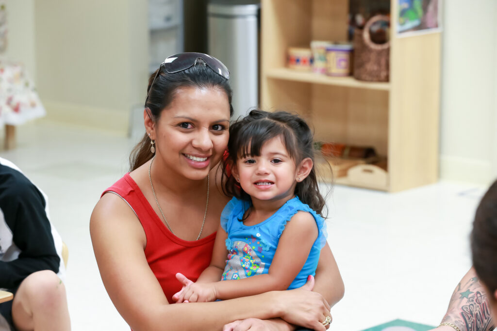 Adult woman smiling and holding a young child.