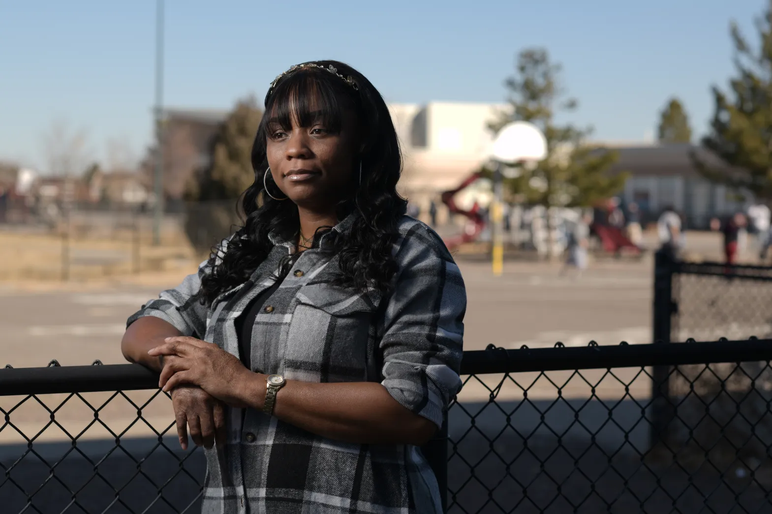 A woman stands by a fence at a park
