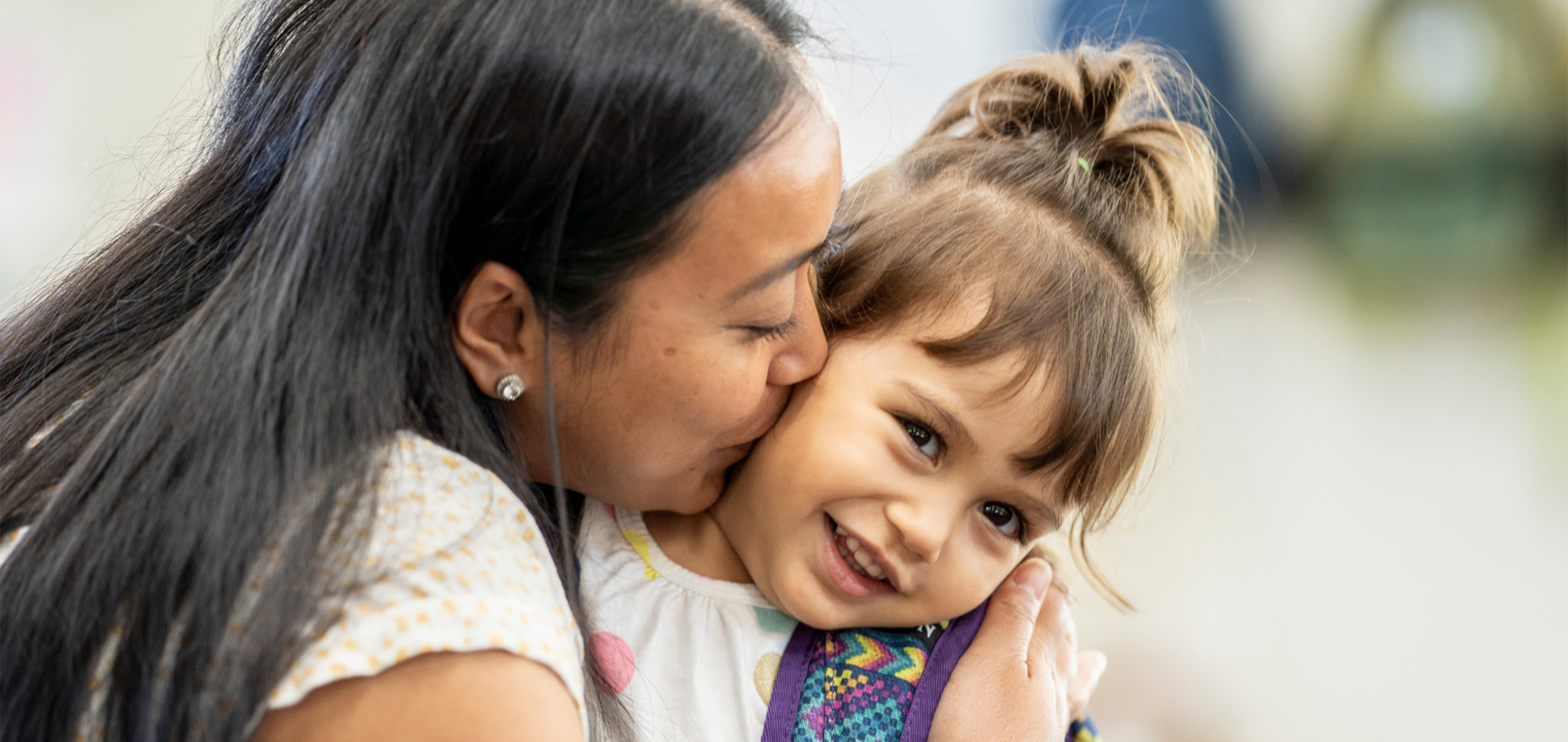 mom hugs daughter and kisses her cheek