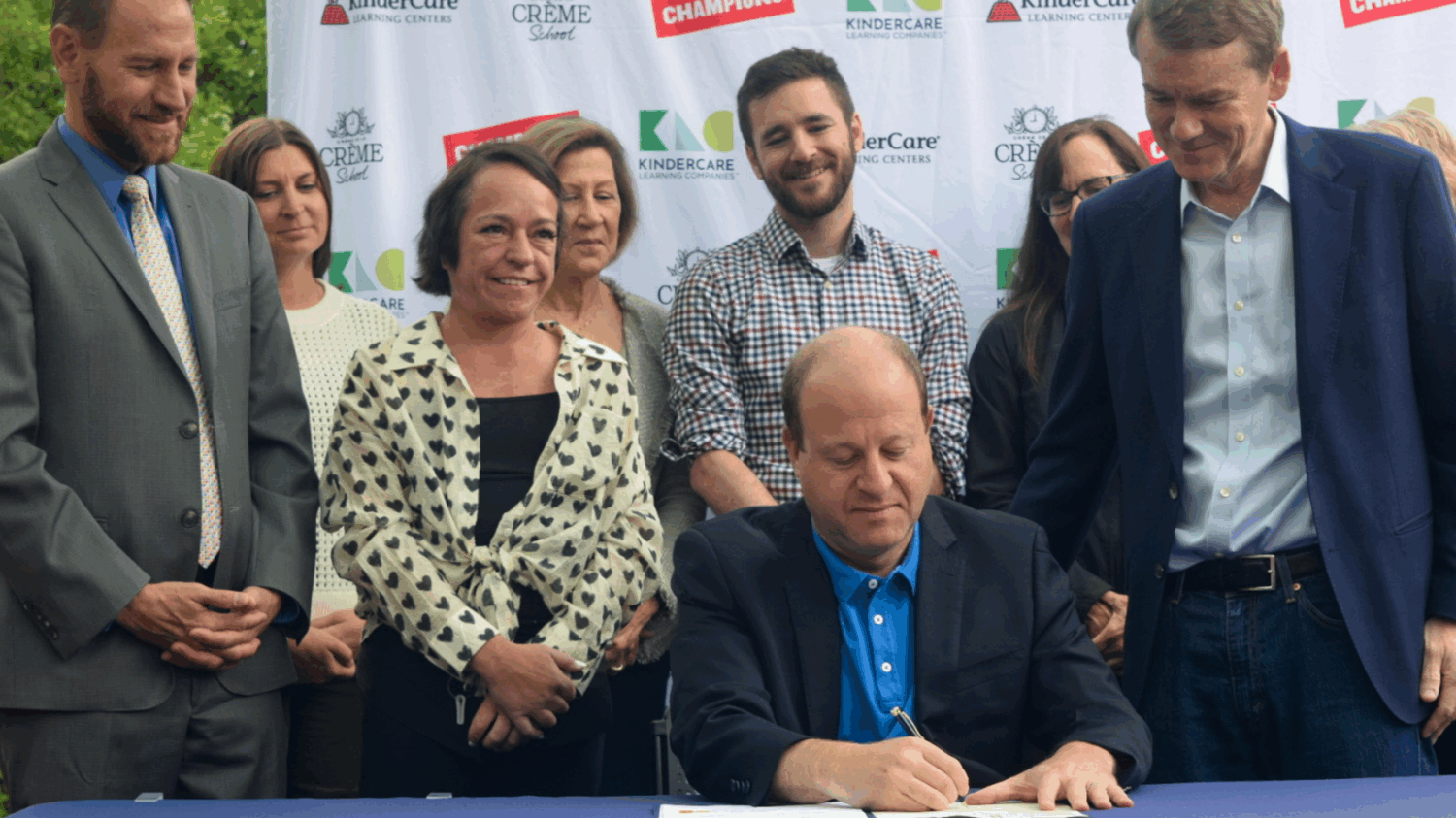 Governor Jared Polis signs the Family Affordability Tax Credit into law. He is surrounded by supporters of the bill.